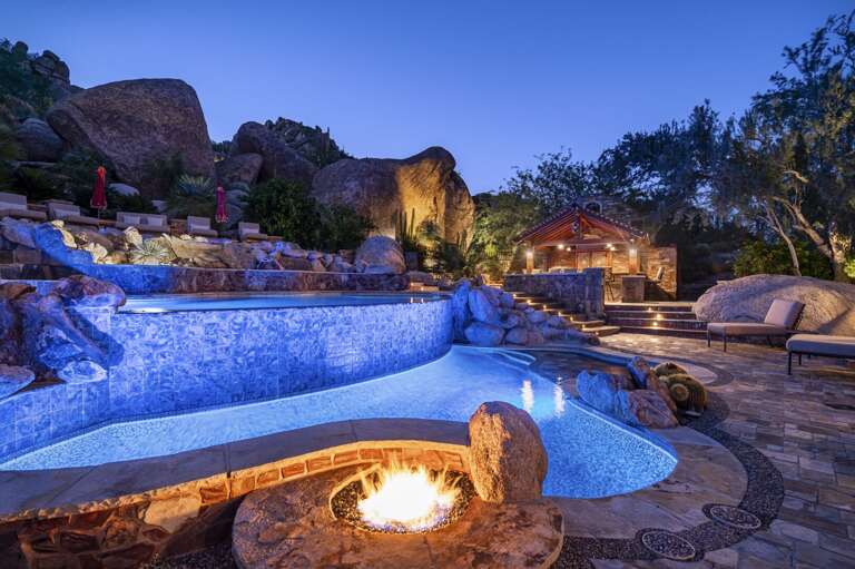 Experience magical desert evenings with illuminated waterfalls, glowing fire features, and luxurious outdoor lounging.