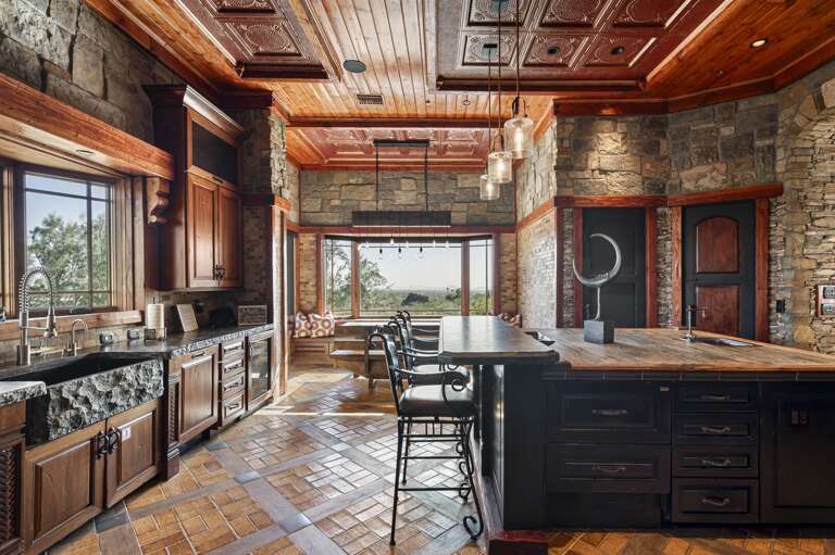 Gather in the beautifully designed gourmet kitchen, featuring rich wood cabinetry, expansive islands, elegant stone finishes, and a charming breakfast nook with stunning desert views.