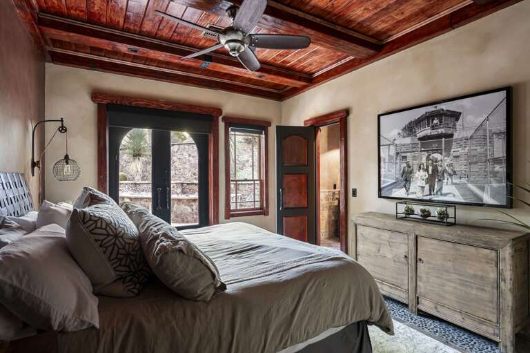 Relax in this inviting bedroom featuring rich wood accents, plush bedding, and private patio access.