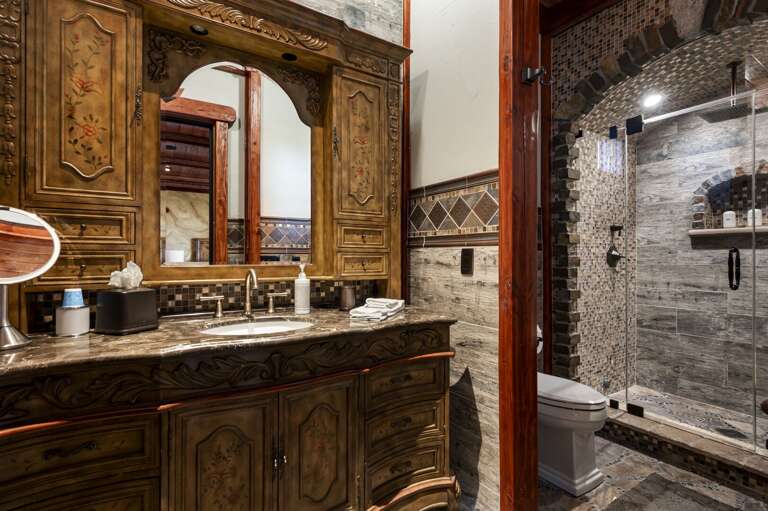 Retreat to this luxurious bedroom featuring a cozy fireplace, elegant wood finishes, and a private p