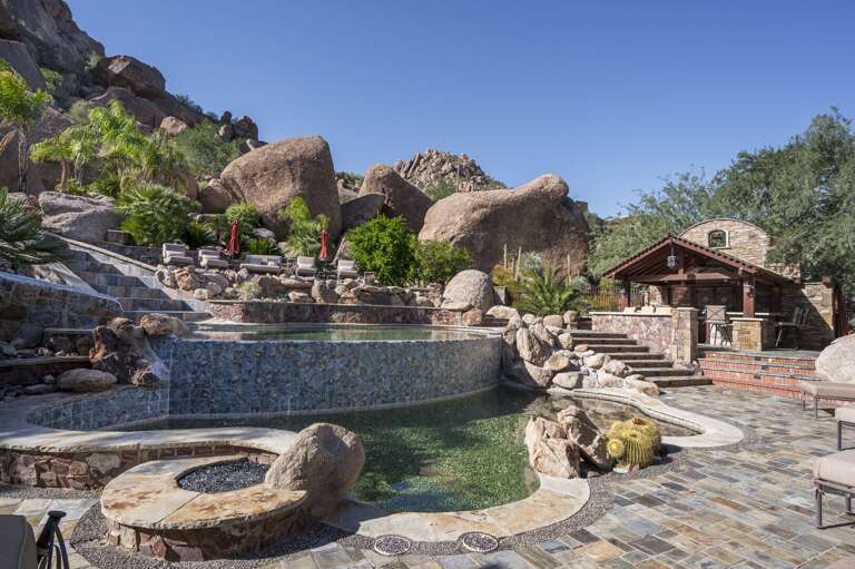 Enjoy a luxurious outdoor retreat featuring a stunning pool, waterslide, and inviting poolside seating.