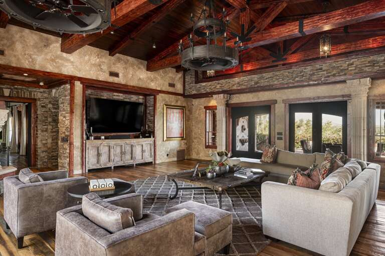 Gather in the spacious living room featuring soaring wood-beamed ceilings, elegant furnishings, and rustic luxury throughout.