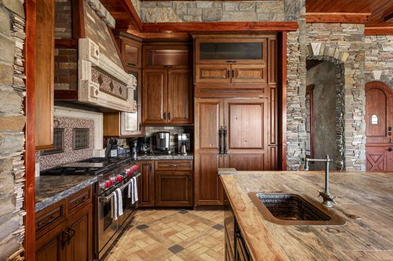 Gather in the beautifully designed gourmet kitchen, featuring rich wood cabinetry, expansive islands, elegant stone finishes, and a charming breakfast nook with stunning desert views.