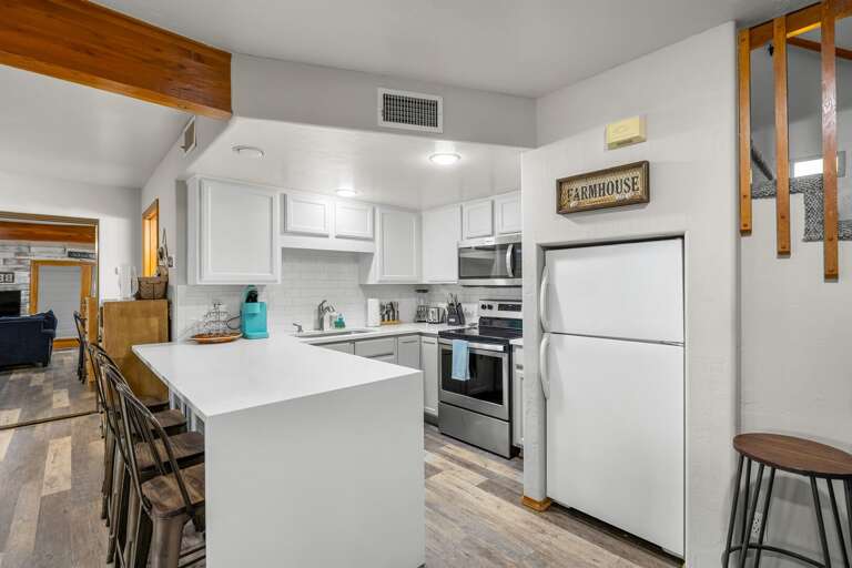 Modern kitchen featuring sleek white quartz countertops, stainless steel appliances, a Keurig coffee maker, and a convenient countertop ice maker.