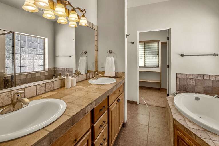 Master Bedroom: King bed, smart TV, walk-in closet, private patio access and en-suite bathroom with a luxurious walk-in shower, jetted bathtub, and dual vanities.