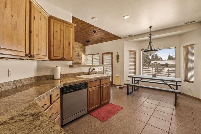Serve meals at the breakfast bar or in the adjacent dining area, flooded with natural light from the surrounding wood-framed windows.