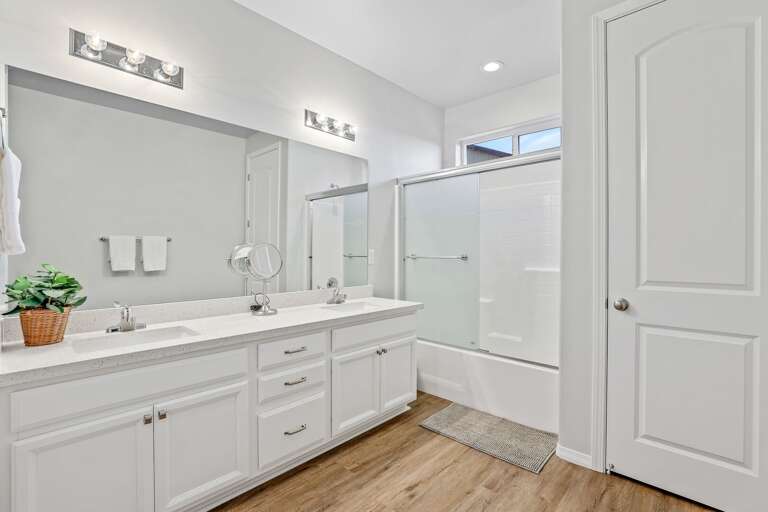 The en-suite bathroom features two sinks with ample counter and storage space, a large walk-in closet, a spacious shower/tub combo, and a private commode room.