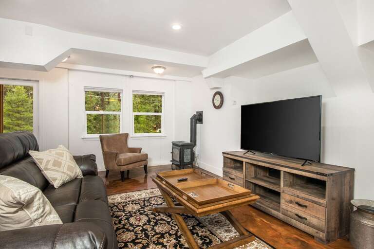 The apartment features epoxy floors, dark wood furnishings, and armchair, and a flat-screen TV.