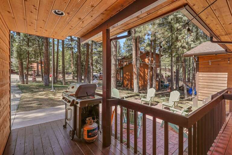 Covered deck with a BBQ grill overlooking a serene outdoor seating area among the pines. Covered deck with a BBQ grill overlooking a serene outdoor seating area among the pines.