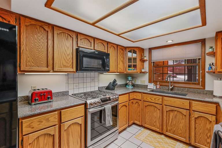 A sleek 5-burner gas range, refrigerator with ice maker and drink dispenser, dishwasher, and above-the-stove microwave. A sleek 5-burner gas range, refrigerator with ice maker and drink dispenser, dishwasher, and above-the-stove microwave.