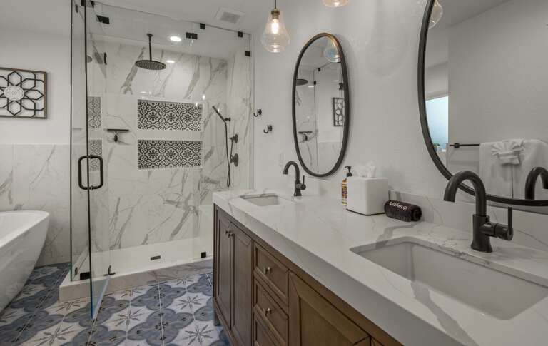 The attached bathroom has two vanities in white marbled quartz , an all-glass shower set in tile The attached bathroom has two vanities in white marbled quartz , an all-glass shower set in tile