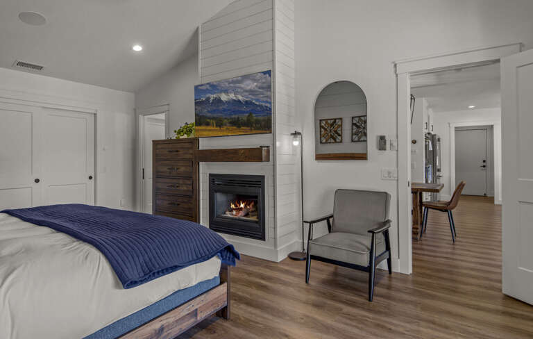A king bed rests between two end tables and faces a stunning gas fireplace and flat screen wall mounted TV A king bed rests between two end tables and faces a stunning gas fireplace and flat screen wall mounted TV