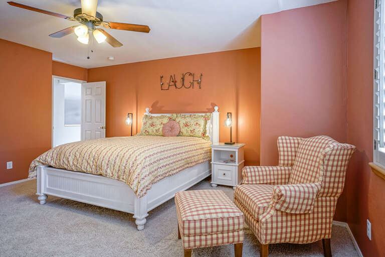 Upper Level: Bedroom 3 – Queen bed, ceiling fan, flat-screen TV atop a charming white armoire, and a cozy, inviting atmosphere. Upper Level: Bedroom 3 – Queen bed, ceiling fan, flat-screen TV atop a charming white armoire, and a cozy, inviting atmosphere.