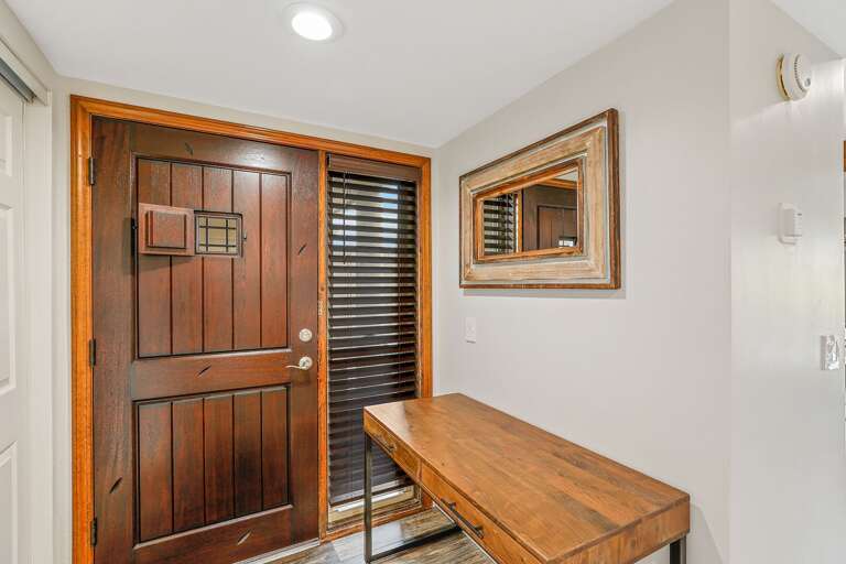 A stunning, strong wooden door opens up into an entryway with a table A stunning, strong wooden door opens up into an entryway with a table