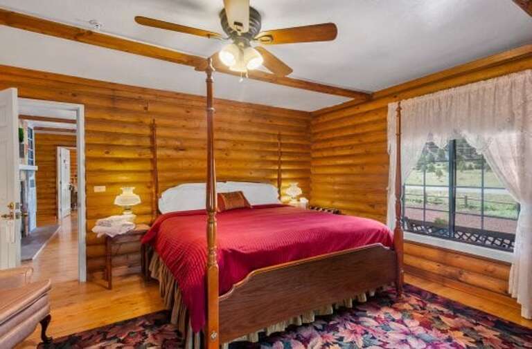 Elegant Rose Room Design: Alder wood floors, a King-sized four-poster bed, and two wing-back chairs.