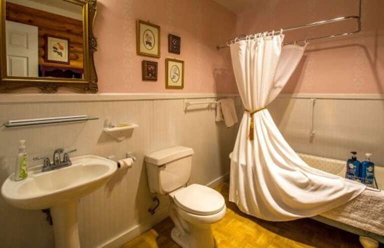 Relax in Comfort: Sleep soundly on a luxurious king bed, then refresh in the private bath with a Victorian claw-foot tub/shower and a classic pedestal sink, combining comfort and style.