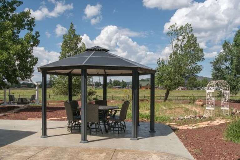 Enjoy outdoor dining with a table for 6 under the backyard gazebo.