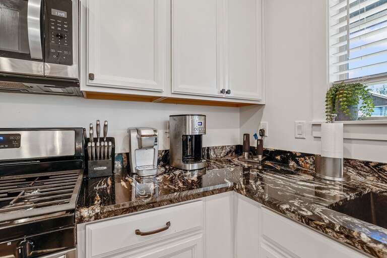 A dark wooden table with seating for six rests under a fun, modern light fixture, creating the perfect spot to enjoy a lovingly cooked meal. A dark wooden table with seating for six rests under a fun, modern light fixture, creating the perfect spot to enjoy a lovingly cooked meal.