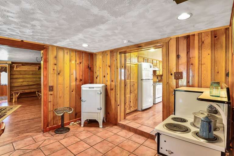 Adjacent is a large dining room with another table and vintage appliances, adding warmth and