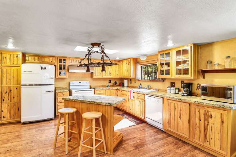 A Chef's Dream Kitchen: A spacious, vintage-style kitchen complete with all modern conveniences, a log dining table, and  a kitchen island for added seating.