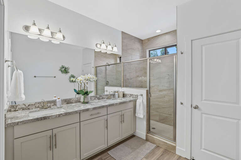 1st Floor Primary Suite 1 (King Bed): En-suite bathroom with dual sinks, walk-in shower, and private toilet room. 1st Floor Primary Suite 1 (King Bed): En-suite bathroom with dual sinks, walk-in shower, and private toilet room.