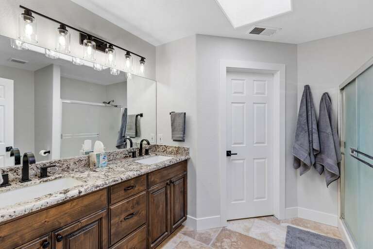 Primary Suite: King-sized bed, smart TV, XL bean bag chair, and en-suite bathroom with dual vanities and a glass shower. Primary Suite: King-sized bed, smart TV, XL bean bag chair, and en-suite bathroom with dual vanities and a glass shower.