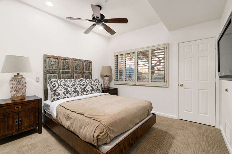 Cozy third bedroom with comfortable bedding, ceiling fan, and natural light for a restful stay.