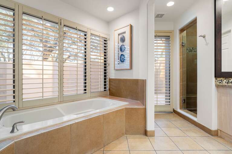 Spacious primary bath featuring a soaking tub, walk-in glass shower, and plenty of natural light.