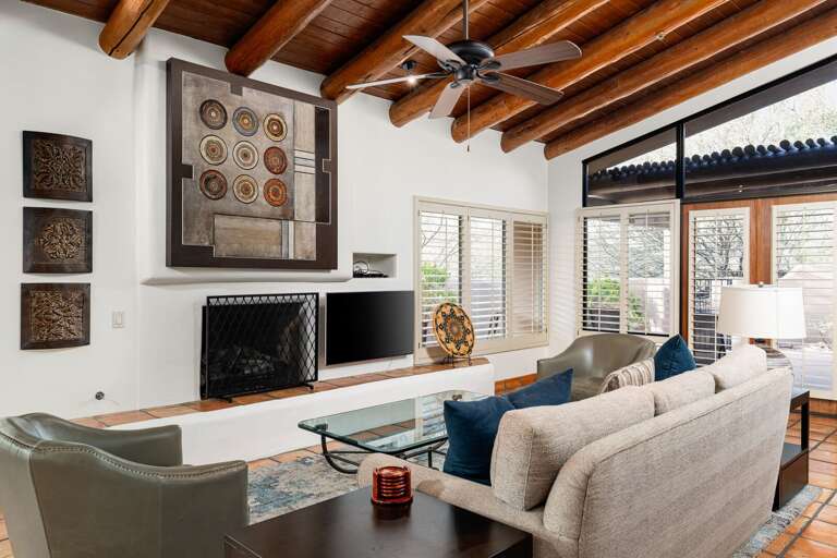 A warm, rustic living room featuring exposed wooden beams, Southwestern-inspired art, and cozy modern furnishings bathed in natural light.