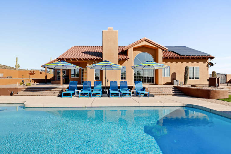 Resort-style backyard with a sparkling pool and plenty of loungers for everyone.