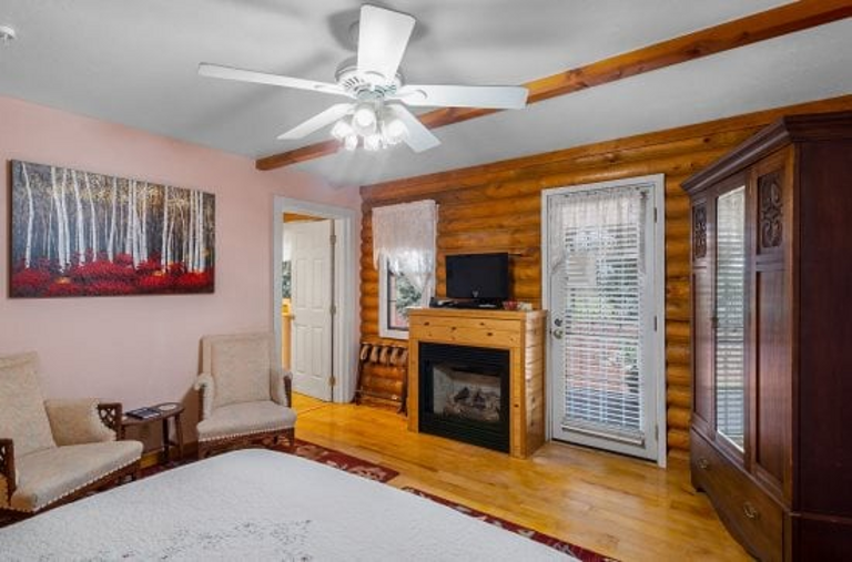 It features a queen bed, a Victorian claw-foot tub, a fireplace in both the room and lobby, and private access to a wrap-around deck with stunning views of Bill Williams Mountain.