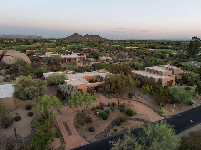 An aerial view showcases the home's spacious lot, lush landscaping, and private setting nestled among the Sonoran Desert.