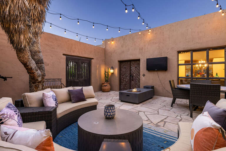 Enjoy Arizona evenings in the beautifully lit courtyard featuring comfortable lounge seating, a fire table, and seamless indoor-outdoor living.