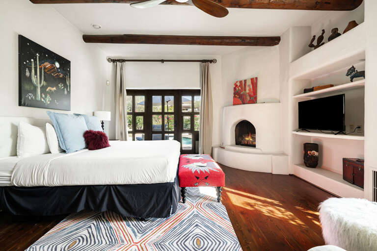 Enjoy a warm fireplace, plush king bed, custom built-ins, and timeless architecture in this beautifully designed primary suite.