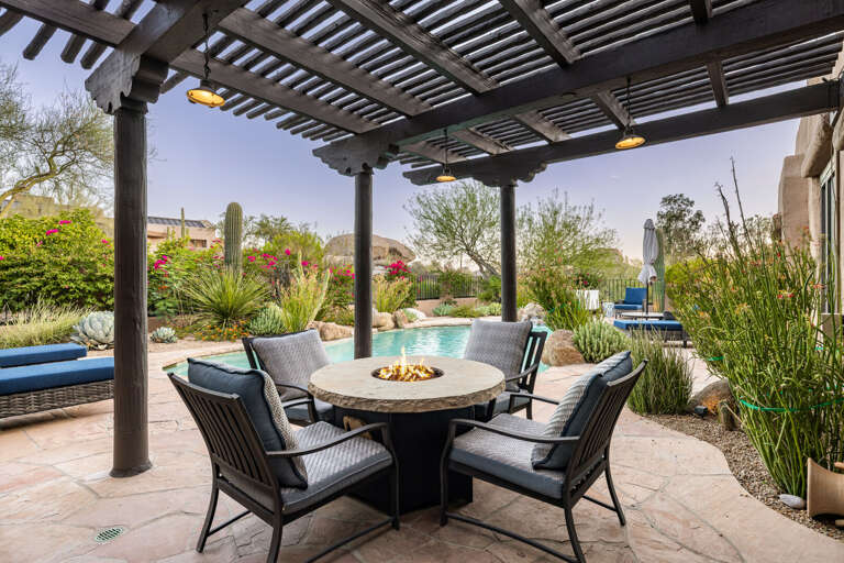 Gather around the fire table beneath the covered patio, offering comfortable seating and the perfect spot to enjoy Arizona evenings.