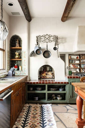 Handcrafted tile, rustic wood accents, and a charming fireplace create a one-of-a-kind kitchen full of authentic Southwestern character.