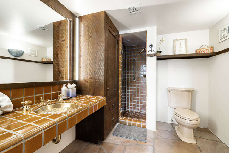 The hidden bedroom includes a spacious ensuite with handcrafted tilework, a walk-in shower, and custom finishes inspired by the Southwest.