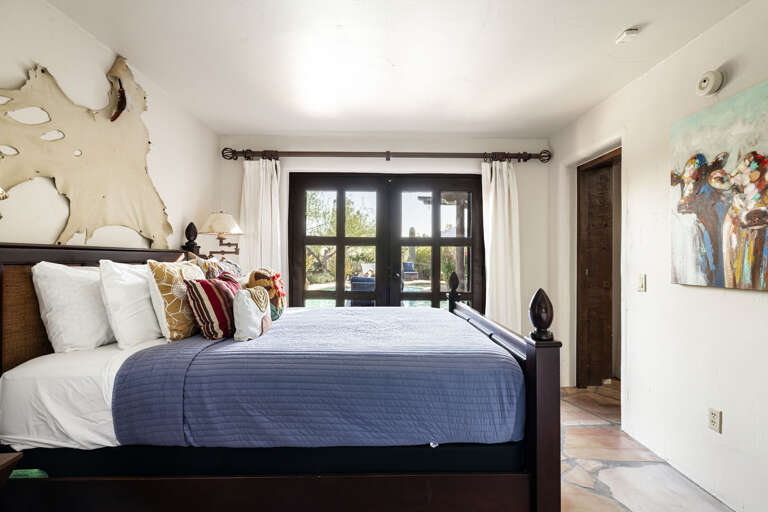 Hidden behind the custom bookcase, this private bedroom features plush bedding, rustic charm, and French doors that fill the space with natural light.