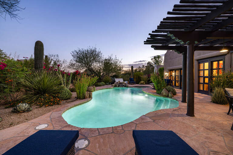 Lounge by the sparkling private pool surrounded by lush desert landscaping, shaded seating, and a peaceful Arizona setting.