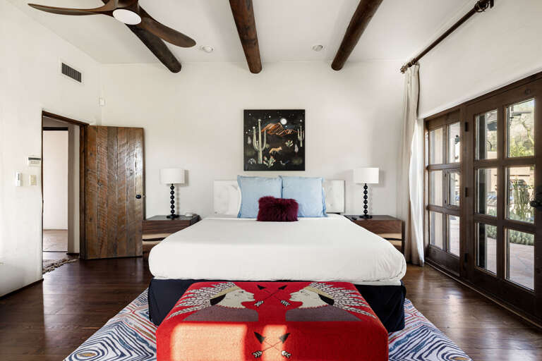 The primary suite blends Southwestern charm with luxury, offering soaring wood beams, abundant natural light, and a peaceful place to unwind.