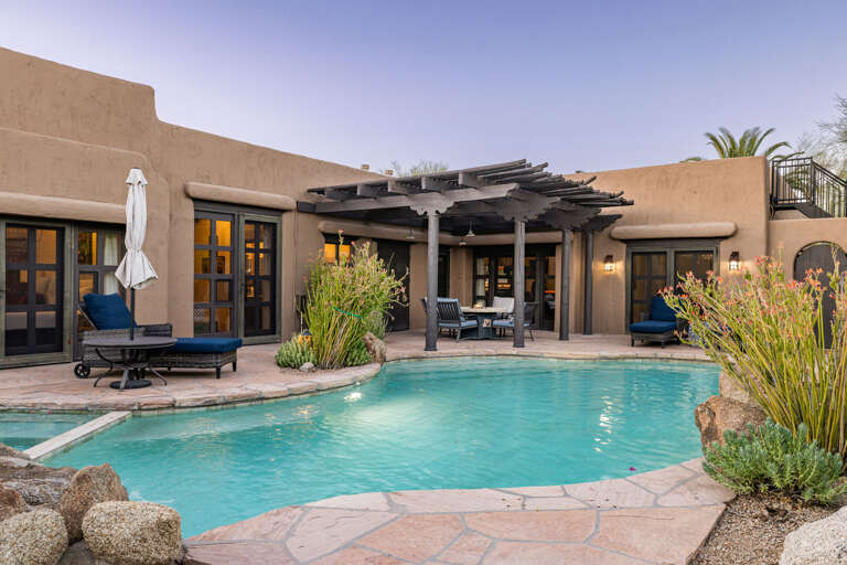 The private backyard features a resort-style pool, covered patio, outdoor seating, and seamless indoor-outdoor living.