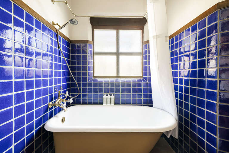 The private ensuite features striking cobalt blue tile, a freestanding soaking tub, and timeless Southwestern character.