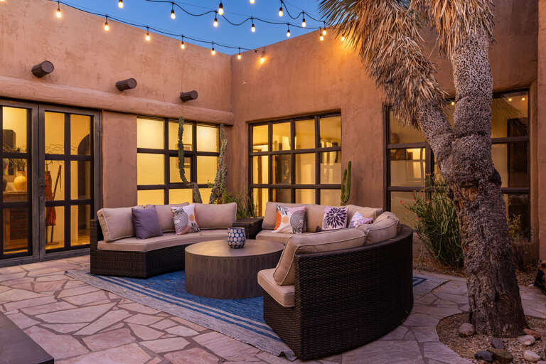 Relax beneath café lights in the private courtyard, featuring comfortable lounge seating and a peaceful setting for evenings under the Arizona sky.