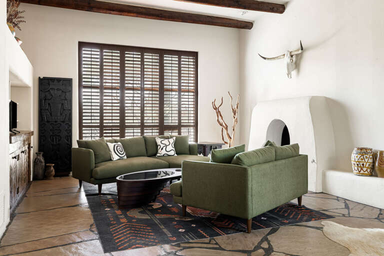 Relax by the kiva fireplace in this stylish living room with comfortable seating, rustic beams, and authentic Southwestern charm.