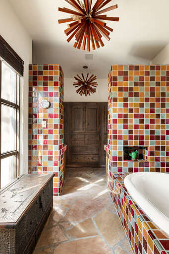 Rich handcrafted tile, custom finishes, and natural light create a warm, spa-like atmosphere in the elegant primary bathroom.