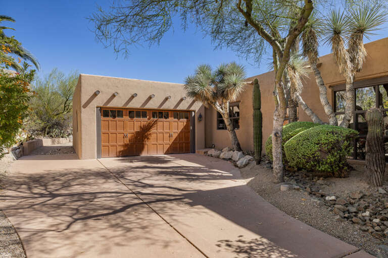 A spacious private driveway and garage provide convenient parking, framed by stunning desert landscaping and classic Southwestern architecture.