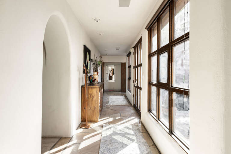 Sun-filled hallways with oversized windows, natural stone floors, and handcrafted details connect the home's thoughtfully designed living spaces.