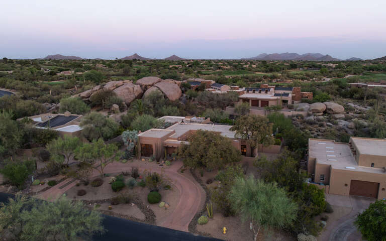 Take in sweeping aerial views of the surrounding desert, rock formations, and the home's beautifully landscaped private grounds.