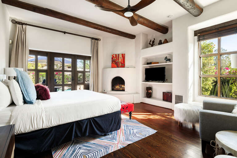 Wake up in the spacious primary suite featuring a king bed, cozy fireplace, seating area, and French doors that open to the backyard oasis.