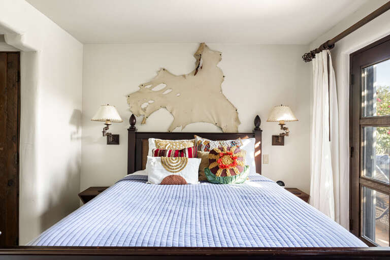A warm and welcoming bedroom featuring plush bedding, natural light, and authentic Southwestern details for a restful night's sleep.